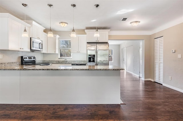 kitchen featuring white cabinetry, dark stone countertops, stainless steel appliances, dark hardwood / wood-style floors, and decorative light fixtures