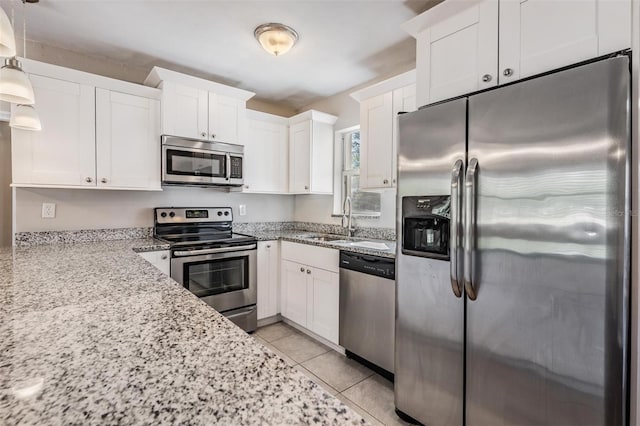 kitchen with pendant lighting, stainless steel appliances, light tile patterned floors, and white cabinets