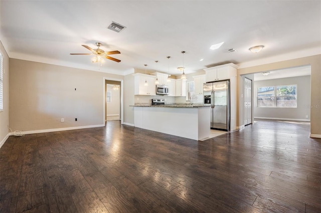 kitchen featuring white cabinetry, hanging light fixtures, appliances with stainless steel finishes, dark hardwood / wood-style floors, and kitchen peninsula