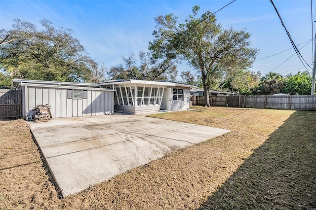 back of property featuring a lawn, a sunroom, and a patio area