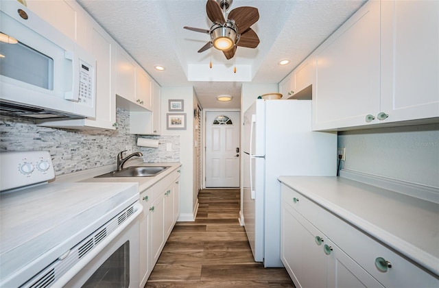 kitchen with white cabinetry, sink, white appliances, and a tray ceiling