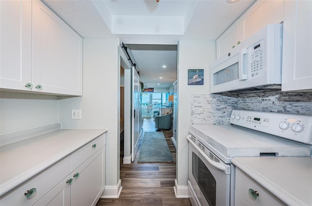 kitchen featuring white cabinetry, white appliances, dark hardwood / wood-style floors, and a barn door