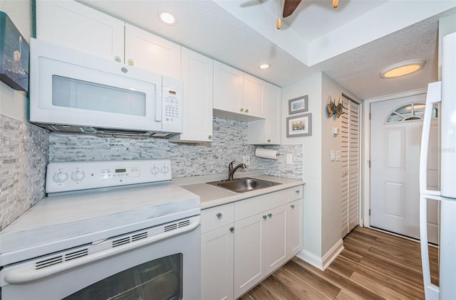 kitchen with sink, white appliances, hardwood / wood-style floors, and white cabinets