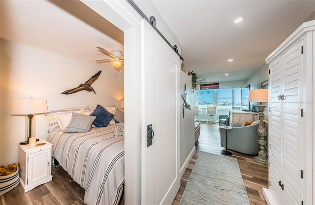 bedroom with a barn door and hardwood / wood-style floors