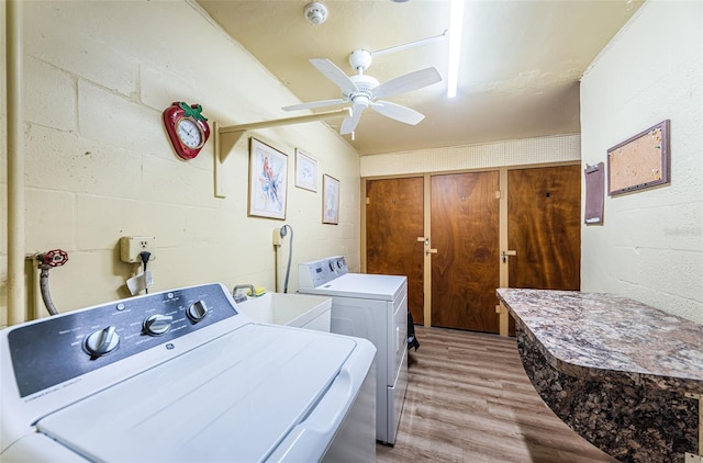 laundry area featuring ceiling fan, sink, washing machine and dryer, and light hardwood / wood-style flooring