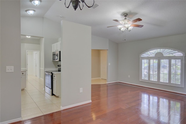 living room with ceiling fan, lofted ceiling, a textured ceiling, and light wood-type flooring