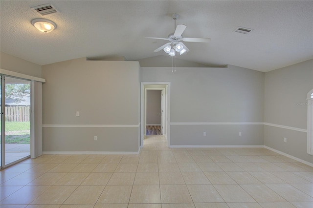 tiled empty room featuring lofted ceiling, ceiling fan, and a textured ceiling