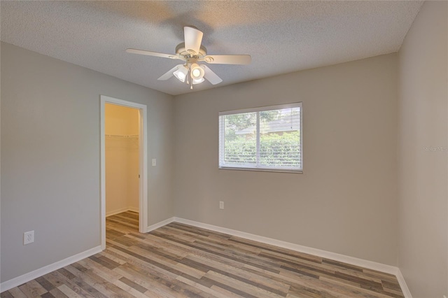 empty room featuring ceiling fan, light hardwood / wood-style flooring, and a textured ceiling