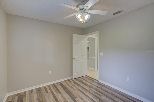 empty room featuring ceiling fan, a textured ceiling, and light wood-type flooring