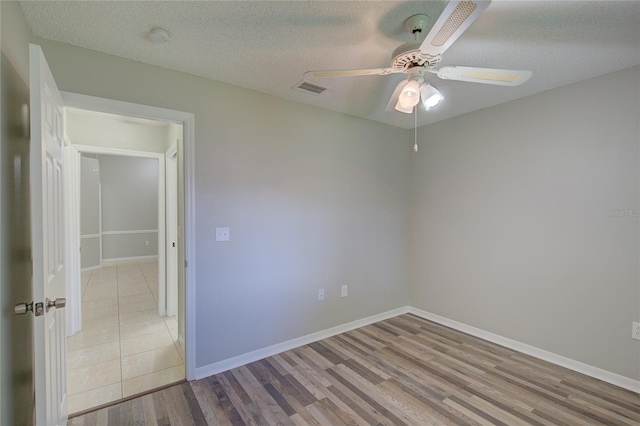 empty room featuring ceiling fan, light hardwood / wood-style floors, and a textured ceiling