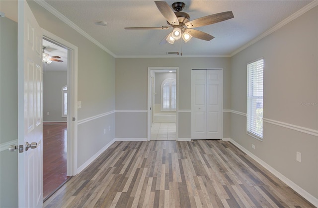 empty room with ornamental molding, ceiling fan, a textured ceiling, and light hardwood / wood-style floors