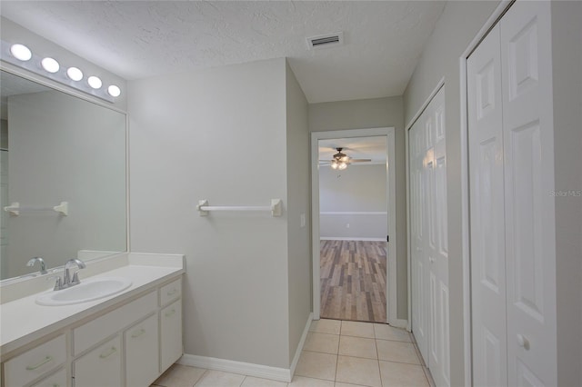 bathroom with ceiling fan, vanity, tile patterned flooring, and a textured ceiling