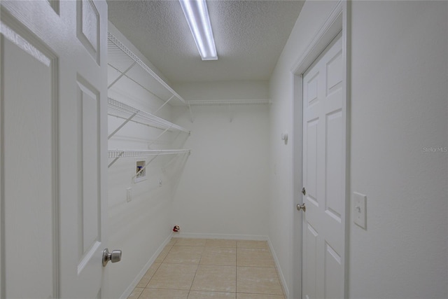 clothes washing area with hookup for a washing machine, light tile patterned flooring, and a textured ceiling