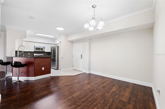 kitchen with light hardwood / wood-style flooring, backsplash, stainless steel appliances, ornamental molding, and white cabinets