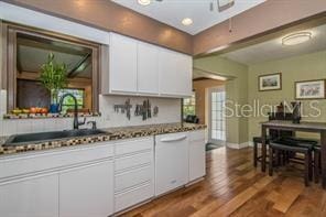 kitchen with dark stone countertops, sink, dark wood-type flooring, and white cabinets