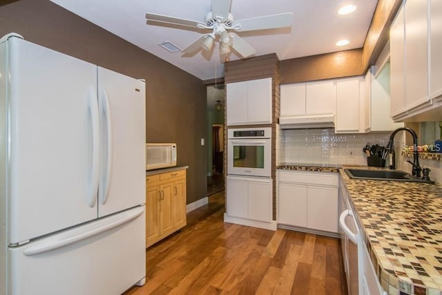 kitchen with tasteful backsplash, sink, light wood-type flooring, white cabinets, and white appliances