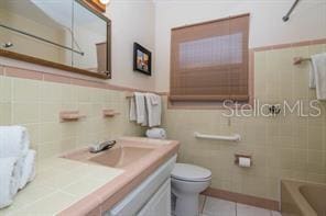 full bathroom with tile walls, tile patterned flooring, vanity, toilet, and bathing tub / shower combination