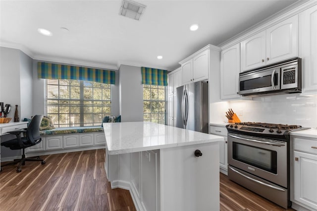 kitchen with appliances with stainless steel finishes, a center island, white cabinets, and decorative backsplash