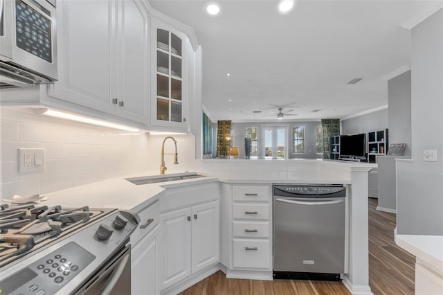 kitchen featuring sink, appliances with stainless steel finishes, white cabinets, kitchen peninsula, and light wood-type flooring