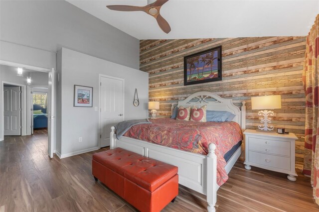 bedroom with lofted ceiling, hardwood / wood-style floors, ceiling fan, and wood walls