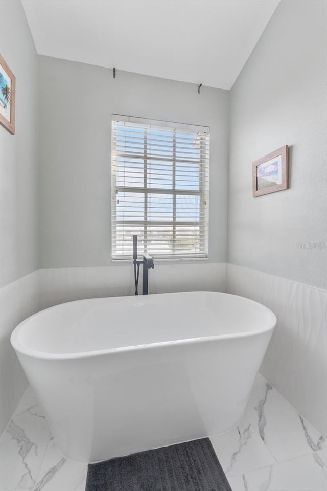 bathroom with a bathing tub and vaulted ceiling