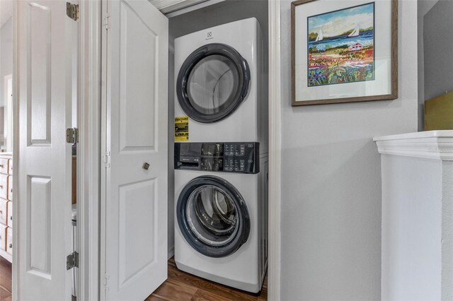 clothes washing area featuring dark hardwood / wood-style flooring and stacked washer / drying machine