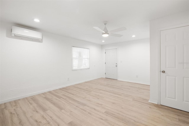 empty room with a wall mounted air conditioner, light hardwood / wood-style floors, and ceiling fan