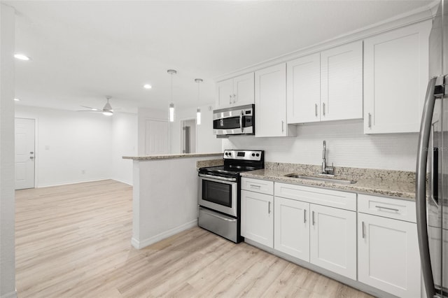 kitchen with stainless steel appliances, sink, white cabinets, and decorative light fixtures