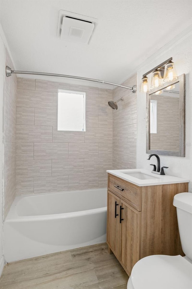 full bathroom featuring vanity, tiled shower / bath, hardwood / wood-style floors, and toilet