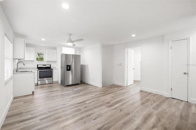 kitchen featuring sink, ceiling fan, stainless steel appliances, light hardwood / wood-style floors, and white cabinets