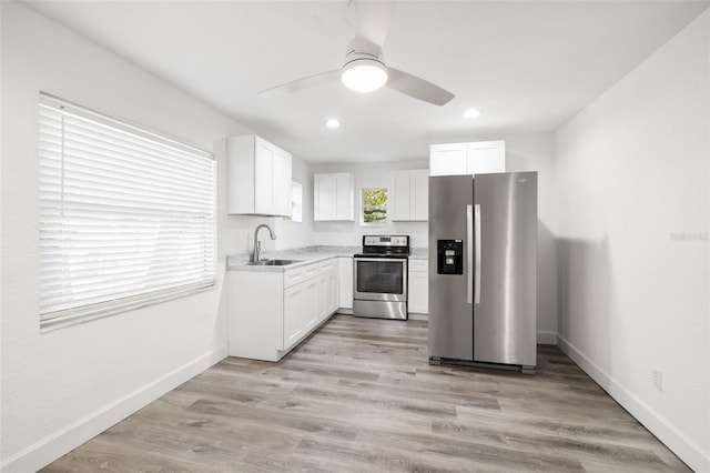 kitchen with stainless steel appliances, sink, white cabinets, and light hardwood / wood-style floors