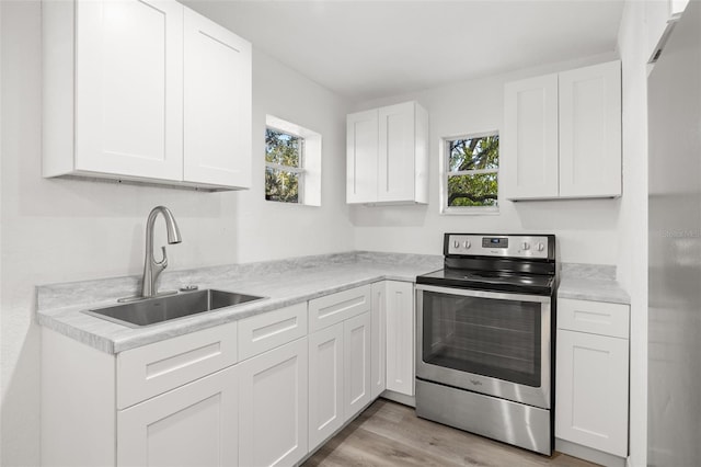 kitchen featuring white cabinetry, sink, a healthy amount of sunlight, and stainless steel range with electric stovetop