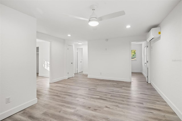 spare room with ceiling fan, a wall mounted air conditioner, and light hardwood / wood-style floors