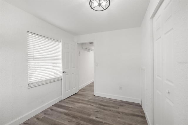 unfurnished bedroom featuring dark hardwood / wood-style flooring, a wall unit AC, and a closet