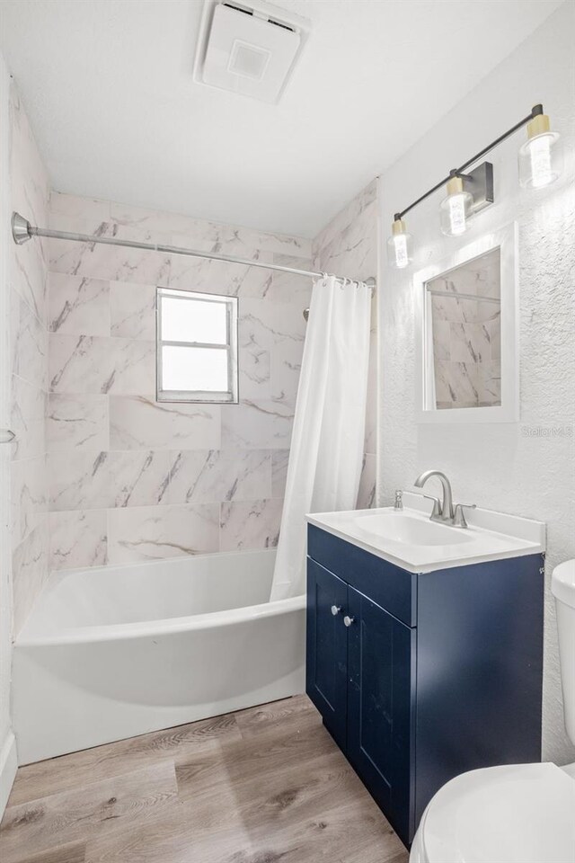 full bathroom with hardwood / wood-style flooring, shower / tub combo with curtain, vanity, and toilet