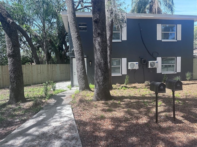 view of home's exterior with a wall mounted air conditioner and fence