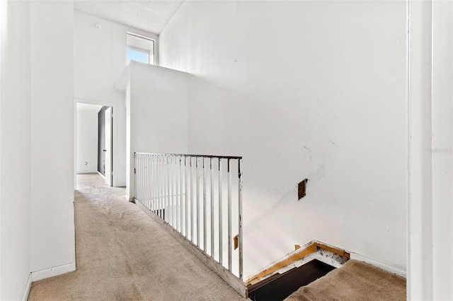 hall with a towering ceiling and light colored carpet