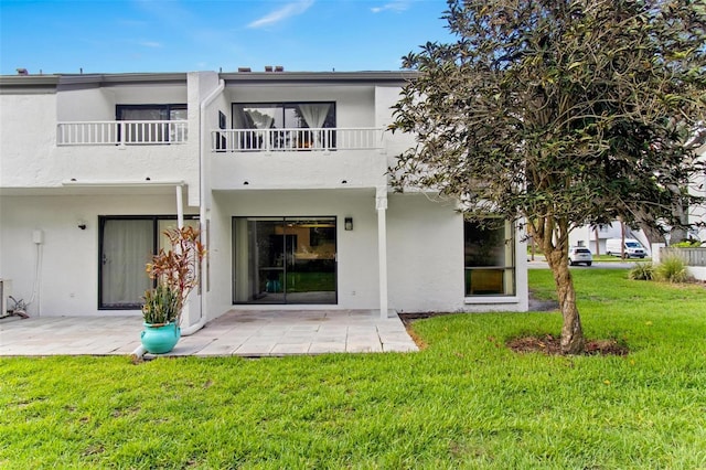 rear view of house with a yard, a patio area, and a balcony