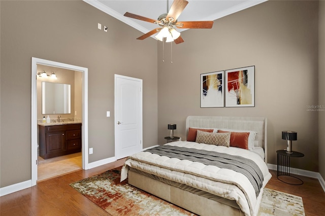 bedroom featuring ceiling fan, a high ceiling, connected bathroom, ornamental molding, and light hardwood / wood-style floors