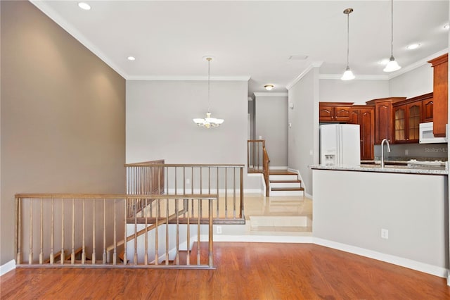 kitchen with light stone counters, an inviting chandelier, wood-type flooring, pendant lighting, and white appliances