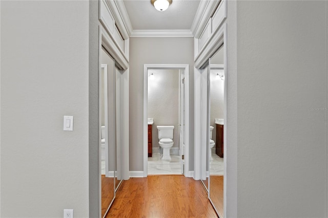 corridor with light hardwood / wood-style flooring and ornamental molding