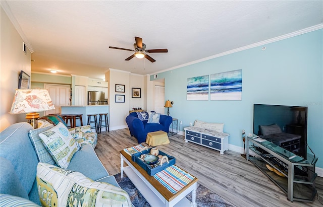 living room featuring crown molding, ceiling fan, and light hardwood / wood-style flooring