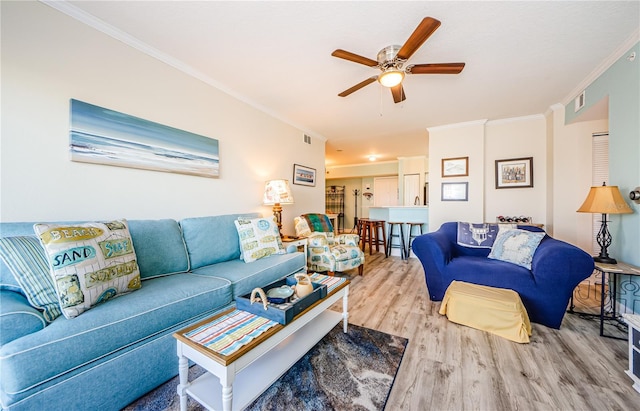 living room featuring crown molding, light hardwood / wood-style floors, and ceiling fan