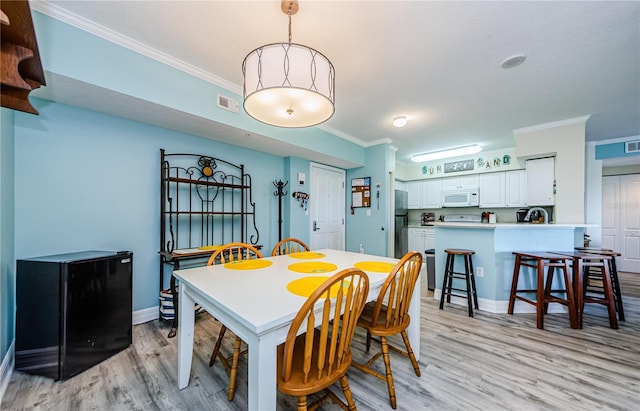 dining area with crown molding, sink, and light hardwood / wood-style flooring