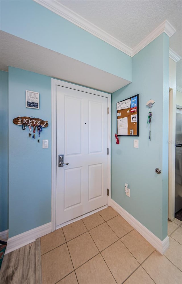 foyer with ornamental molding, a textured ceiling, and light tile patterned floors