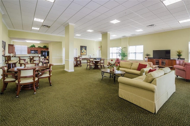 living room with crown molding, dark carpet, a drop ceiling, and ornate columns