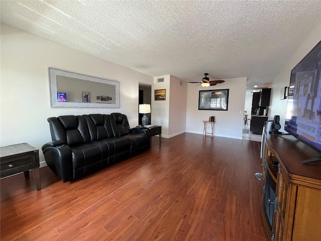 living room with hardwood / wood-style flooring, ceiling fan, and a textured ceiling