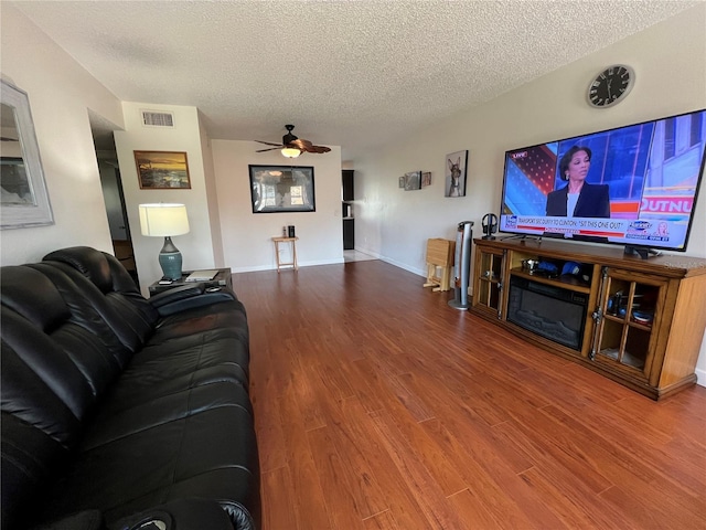 living room featuring ceiling fan, hardwood / wood-style flooring, and a textured ceiling