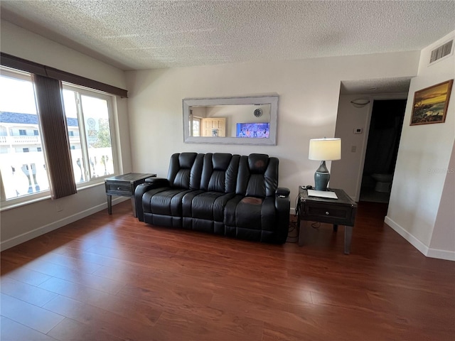 living room featuring dark wood-type flooring and a textured ceiling