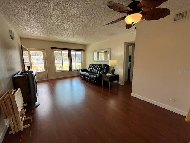 living room featuring ceiling fan, dark hardwood / wood-style flooring, and a textured ceiling